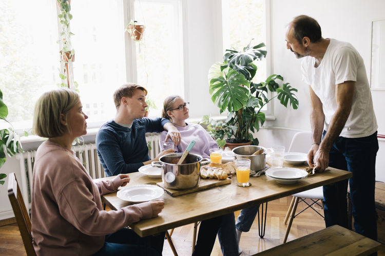 Family talking with dad standing near table at home