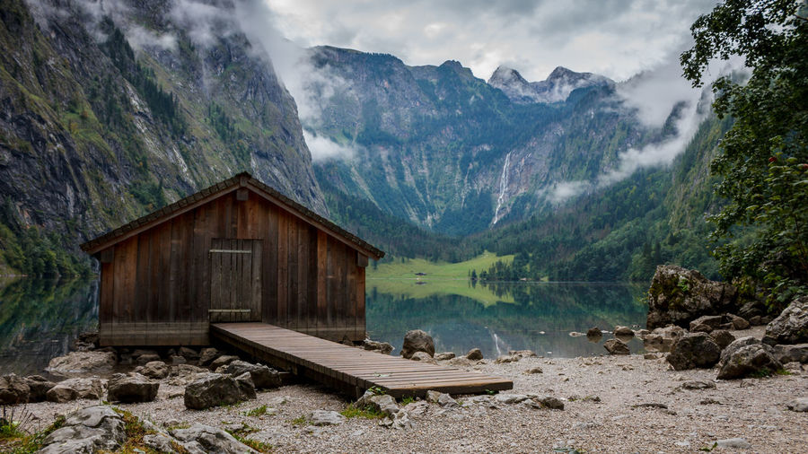 Scenic view of log cabin by lake against mountains