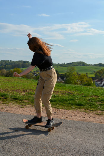 Girl rides a skateboard on a country road in green nature