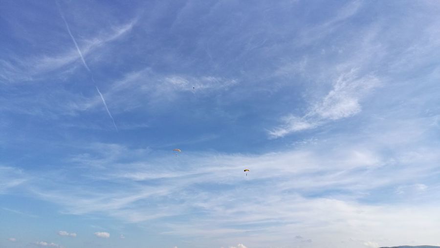 Two distant people paragliding in the sky 