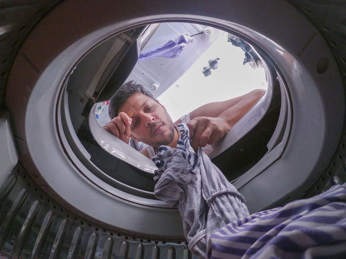 Low angle view of man removing clothes from washing machine