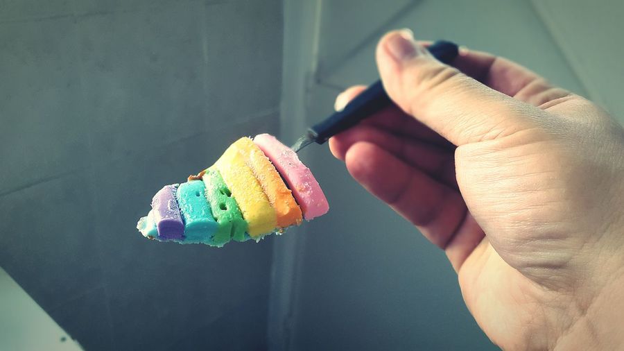 Cropped hand of person holding colorful ice cream