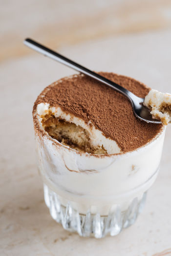 From above delicious traditional coffee flavored dessert tiramisu served in glass cup on table