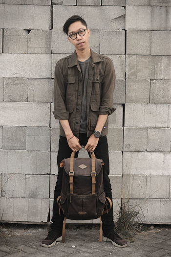 Portrait of young man standing against wall