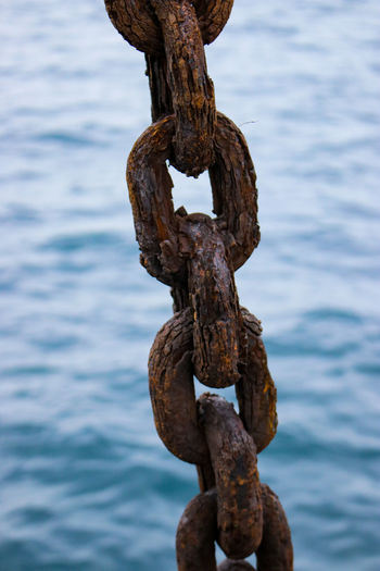 Close-up of rusty chain against sea