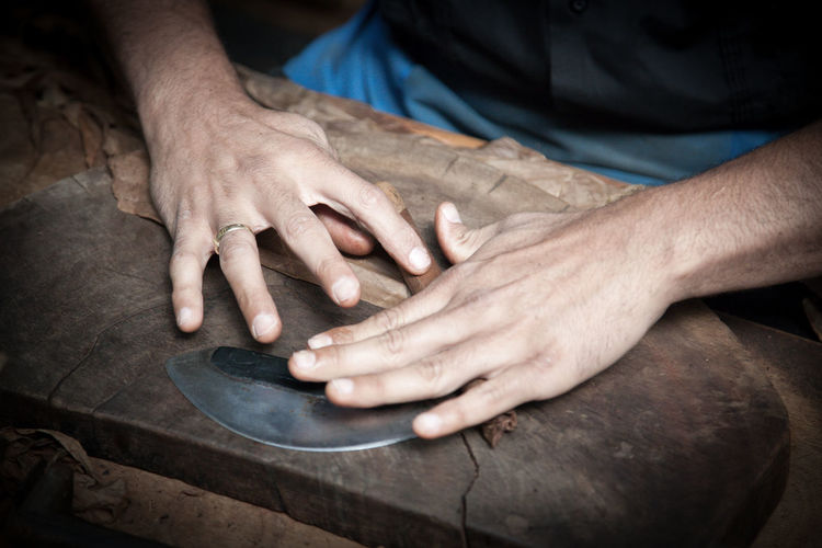 Midsection of worker making cigar