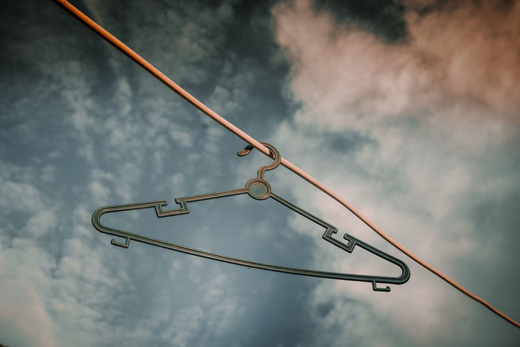Low angle view of coathanger against sky