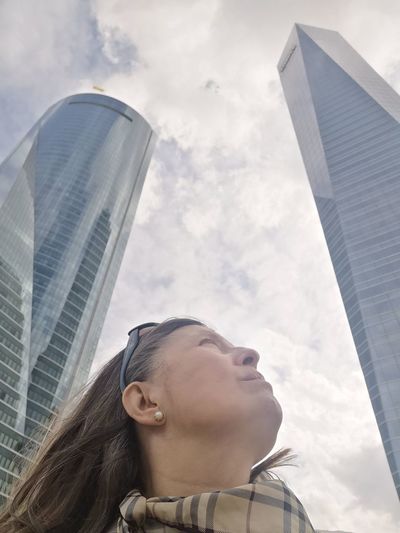 Low angle view of young woman standing against sky