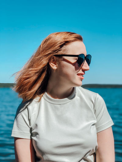 Young woman wearing sunglasses against sea