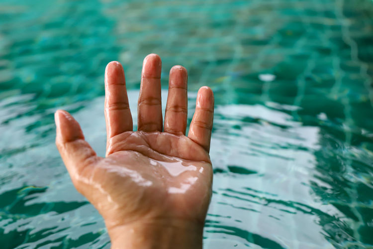 Close-up of person hand in swimming pool