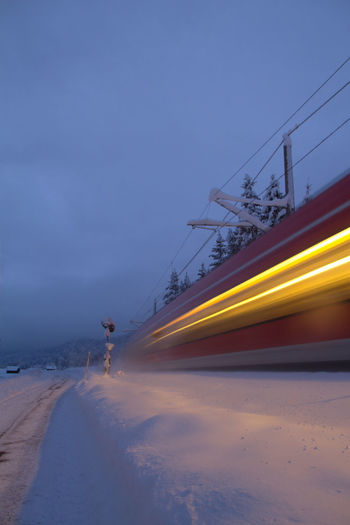 Light trails on road by sea against sky during winter