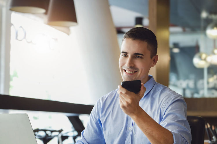 Portrait of young man using mobile phone in office