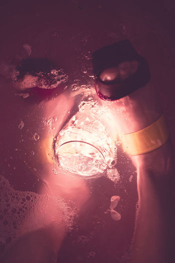 Low section of young woman with illuminated lighting equipment in bathtub