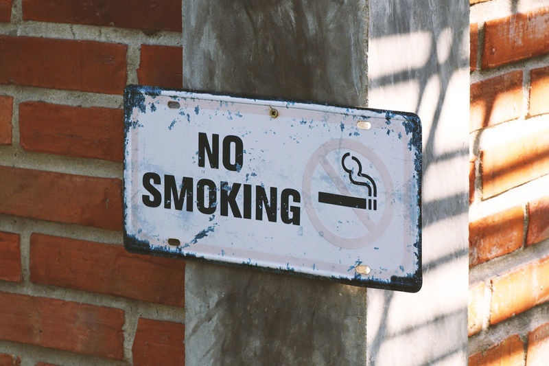 Old rusty metal no smoking sign on the brick wall