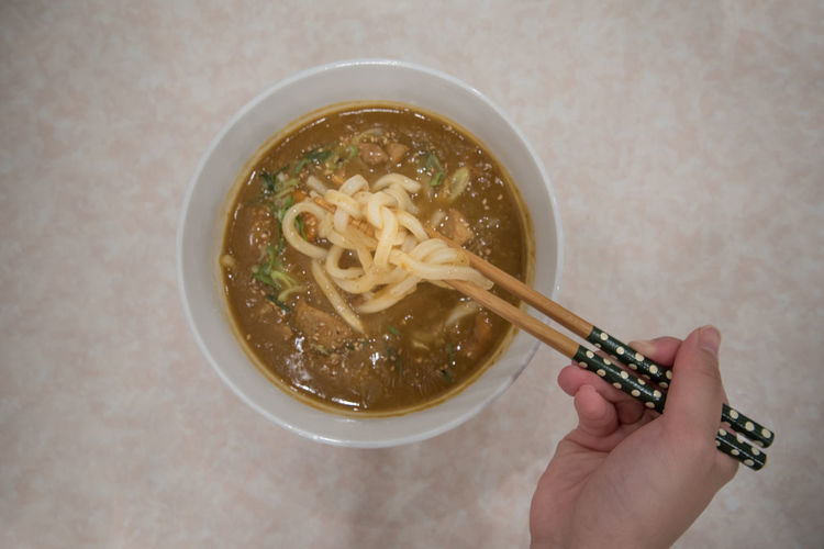Cropped hand having noodles in bowl