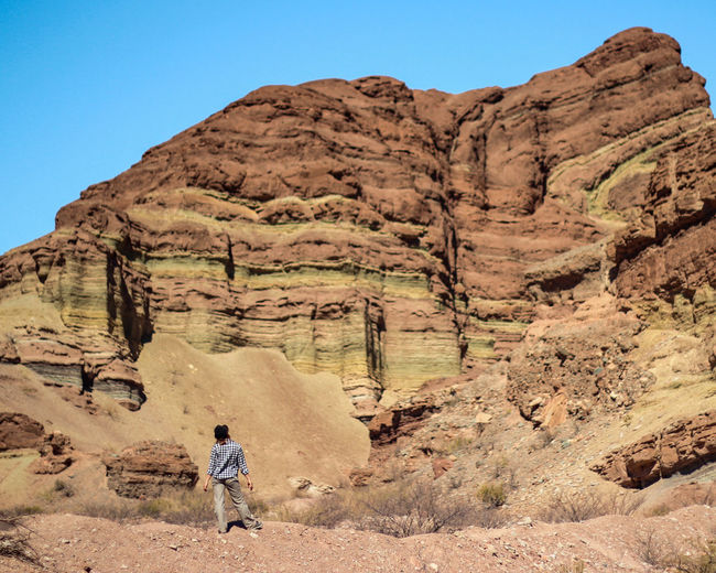 Full length rear view of man walking on rocks