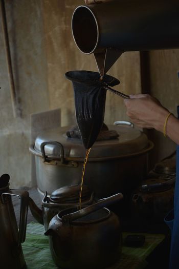 Cropped hand of woman pouring coffee in pot