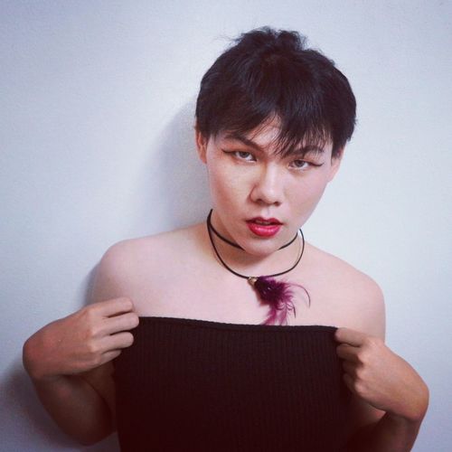 Portrait of transgender man wearing dress against white wall
