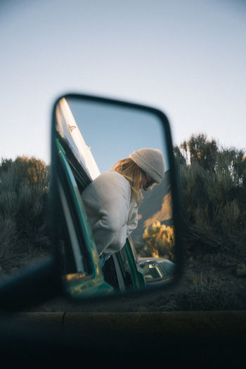 Woman reflecting on side-view car mirror