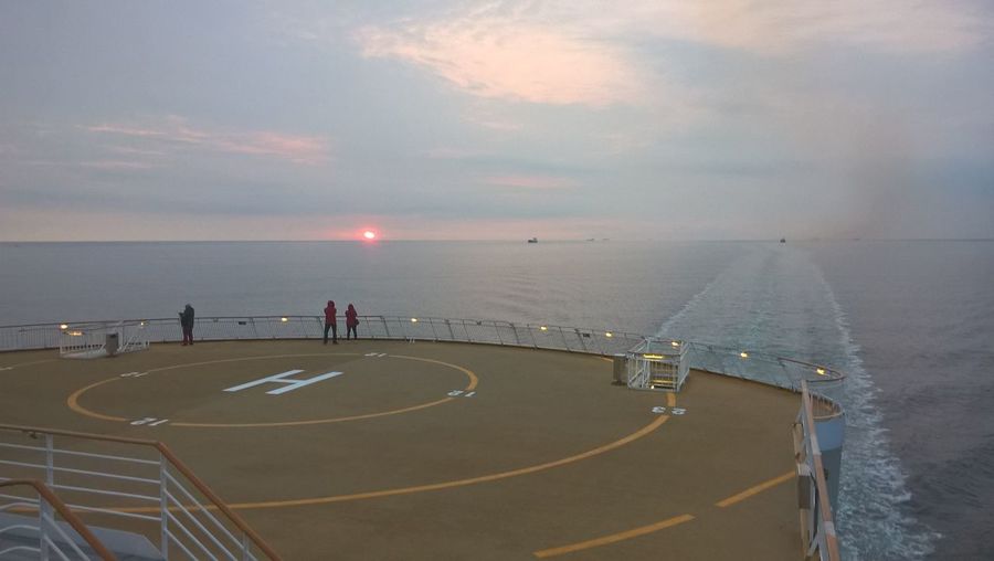 Helipad on ship in sea against sky during sunset