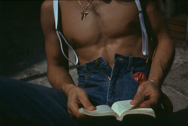 Midsection of shirtless man reading book