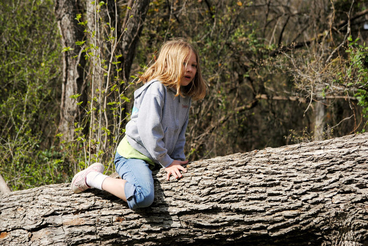 Girl sitting on tree trunk