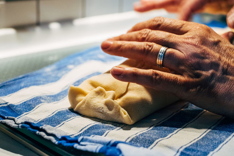 Close up of human hand preparing dough on table