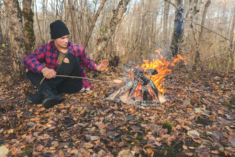 Man roasting food in campfire at forest
