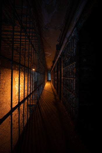 Dark hallway of prison bars in front of cells in an unknown prison cell block