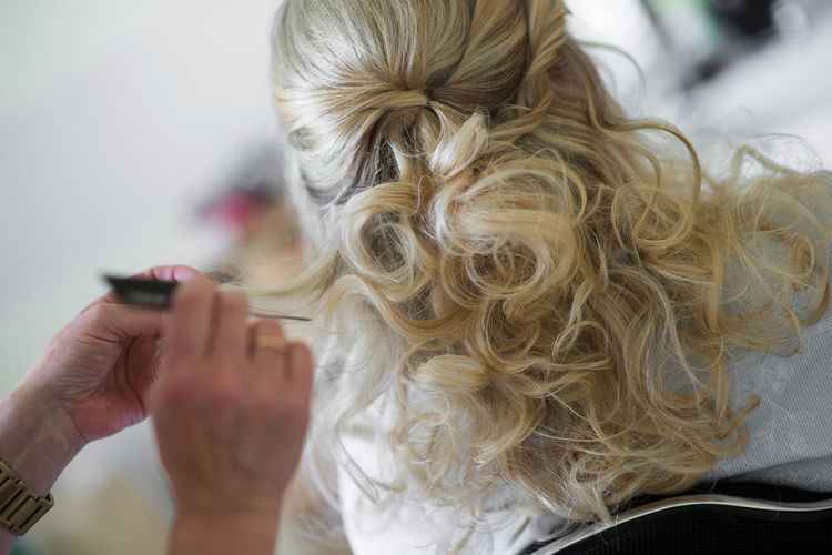 Cropped image of hairdresser styling customer hair in salon