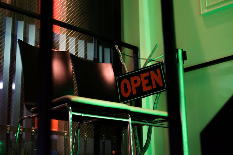 Low angle view of open sign and chairs in restaurant