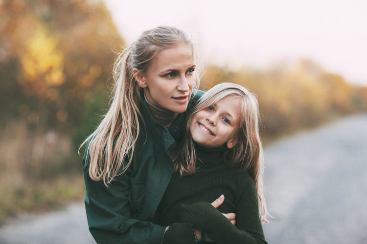 Portrait of happy mature mom and her blonde little daughter hugging and laughing
