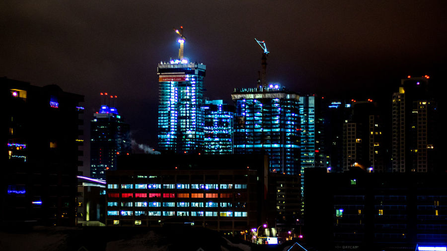 Illuminated cityscape against sky at night