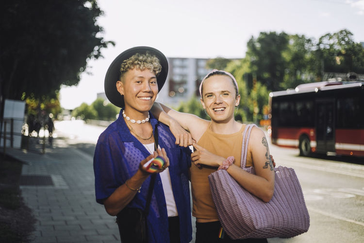 Portrait of happy non-binary person standing by young man wearing hat