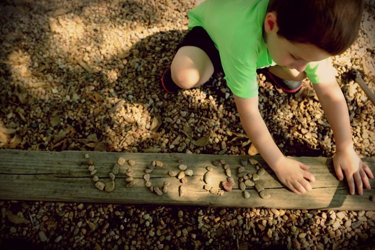 Young boy playing with pebbles in a park