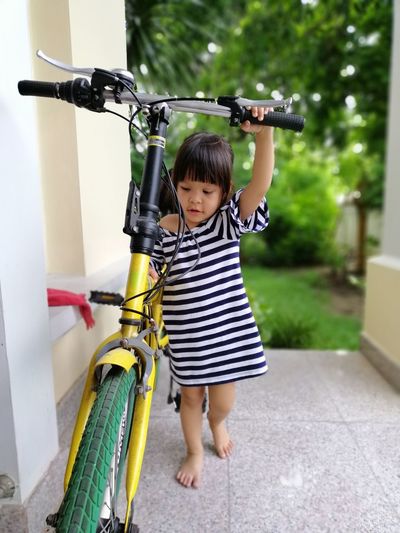 Cute girl walking on footpath with bicycle