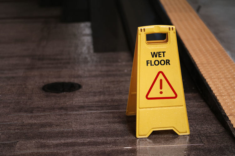 Close-up of warning sign on wooden floor
