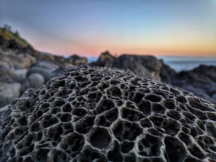 Close-up of rocks on beach against sky during sunset