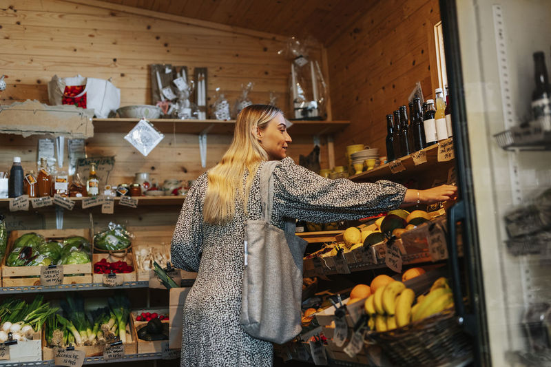 Smiling woman choosing vegetables in shop