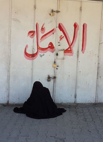 Woman in hijab sitting in front of closed door