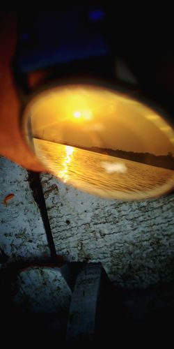 Close-up of lit candles on glass against sunset