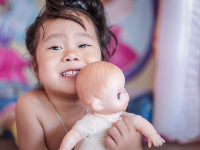 Close-up portrait of cute girl playing with doll