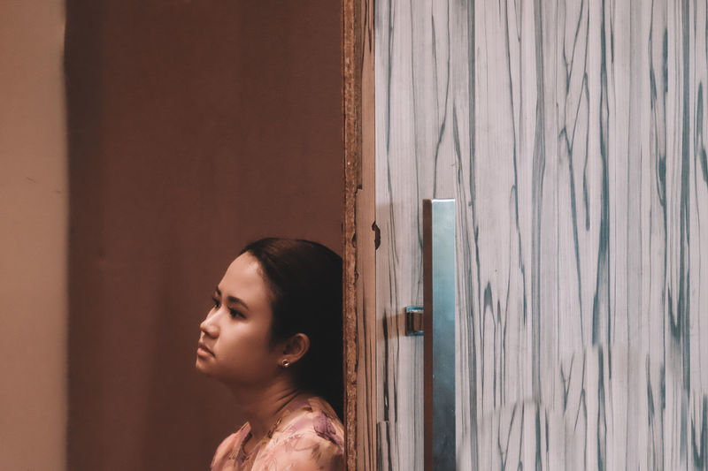 Thoughtful woman leaning on wooden door
