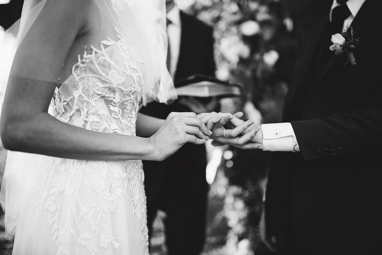 Midsection of bride and groom exchanging rings