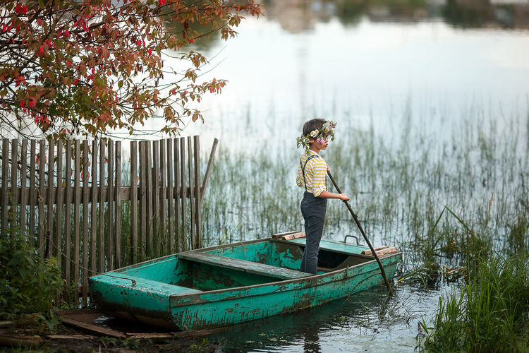 Boy standing by boat in lake
