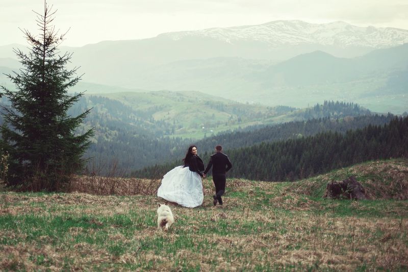 Couple walking on field against mountains