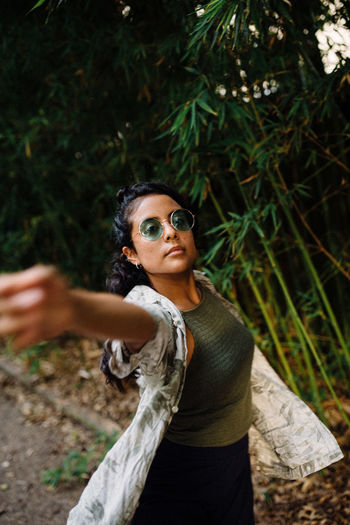 Latina girl with green sunglasses dancing surrounded by green leaves