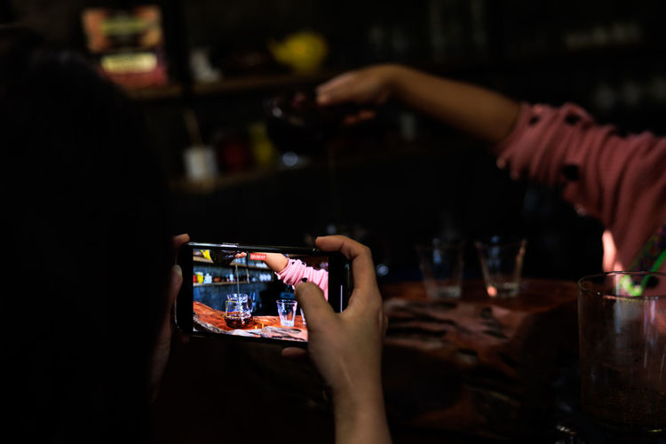 Female tourist using smartphone to record video of tea maker in counter cafe community at chiang 