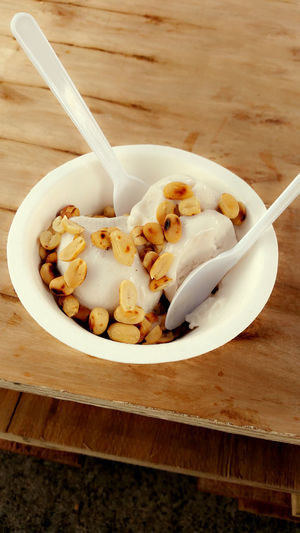 High angle view of fresh coconut ice cream with roasted peanut served on table