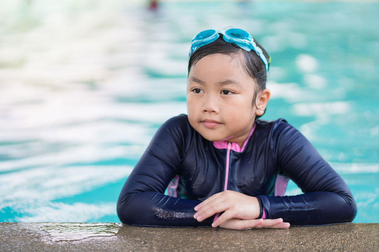 Portrait of cute girl sitting on swimming pool